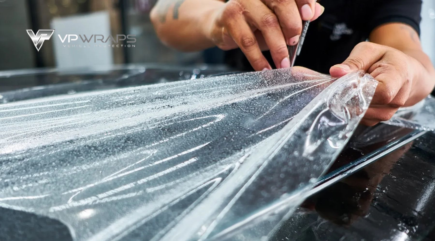 Close-up of a professional installing paint protection film on a vehicle's hood in Magnolia, TX, showing the precise application of the clear protective layer. This image illustrates the hands-on process that answers the question: What Is Paint Protection Film in local vehicle care.