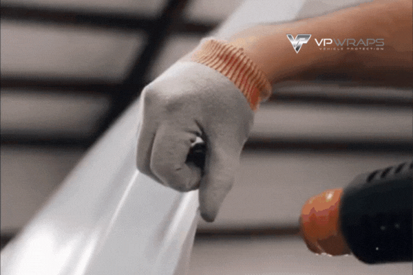 Close-up of a VP Wraps technician in Magnolia, TX stretching paint protection film with a heat gun for flawless application. This clip illustrates what is paint protection film and highlights the precision and care involved in professional PPF installation.