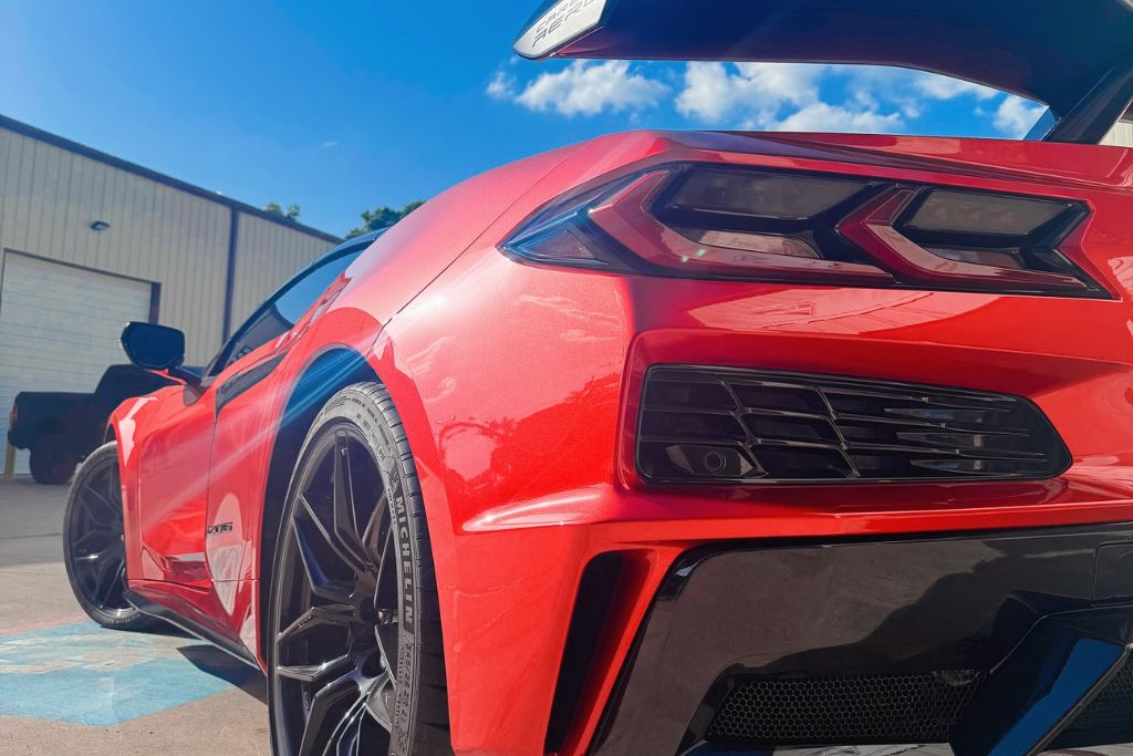 Glossy red sports car parked outside in Magnolia, TX, showcasing a flawless paint finish protected by paint protection film. The image demonstrates the value of PPF in shielding against harsh sun, road debris, and local weather—answering what is paint protection film in a real-world context.